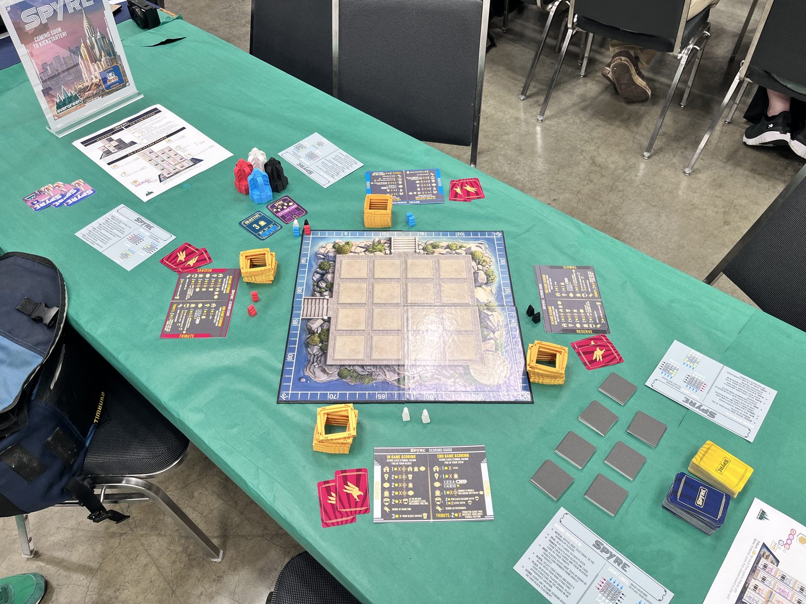 A Spyre demo table set up at Gen Con, with the board, player aids, tiles, and tower pieces laid out on a green tablecloth.